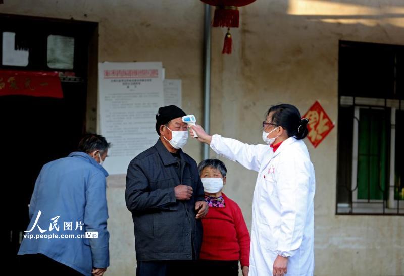 2月20日，在安徽省宣城市宣州区洪林镇宣茶村老党员姜纪华为村民测量体温。